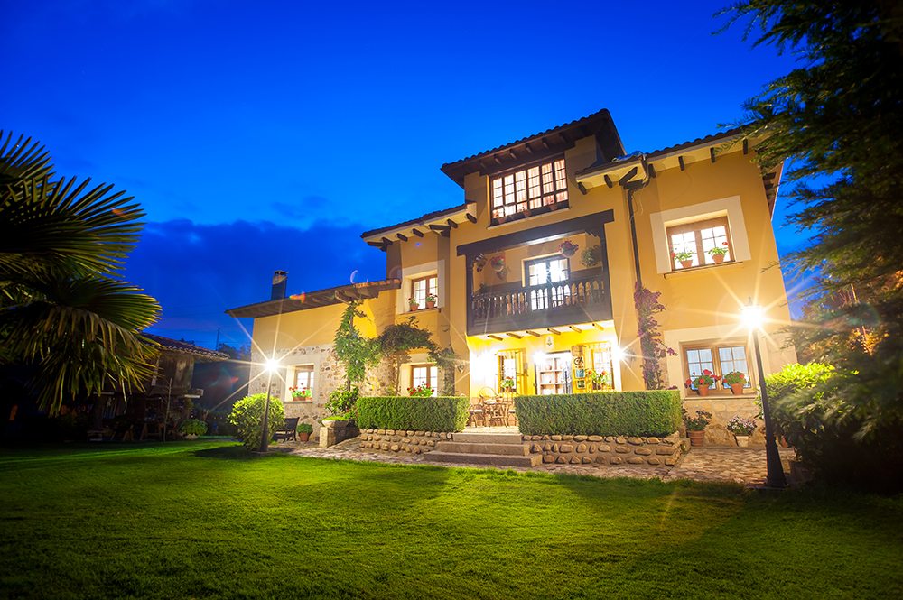 Fachada de la casa y jardín al anochecer